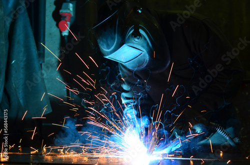 Workers wearing industrial uniforms and Welded Iron Mask at Steel welding plants, industrial safety first	