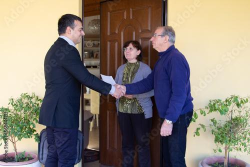 Image of a sales rep and door-to-door salesman explaining his products for sale to an older couple. Harassing seller and scammer.
