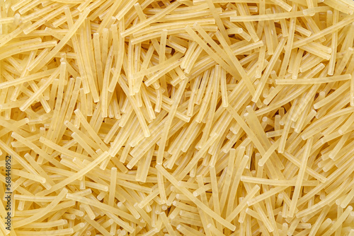 Pasta raw, vermicelli, background uniform texture, small cylinders in bulk close-up, top view