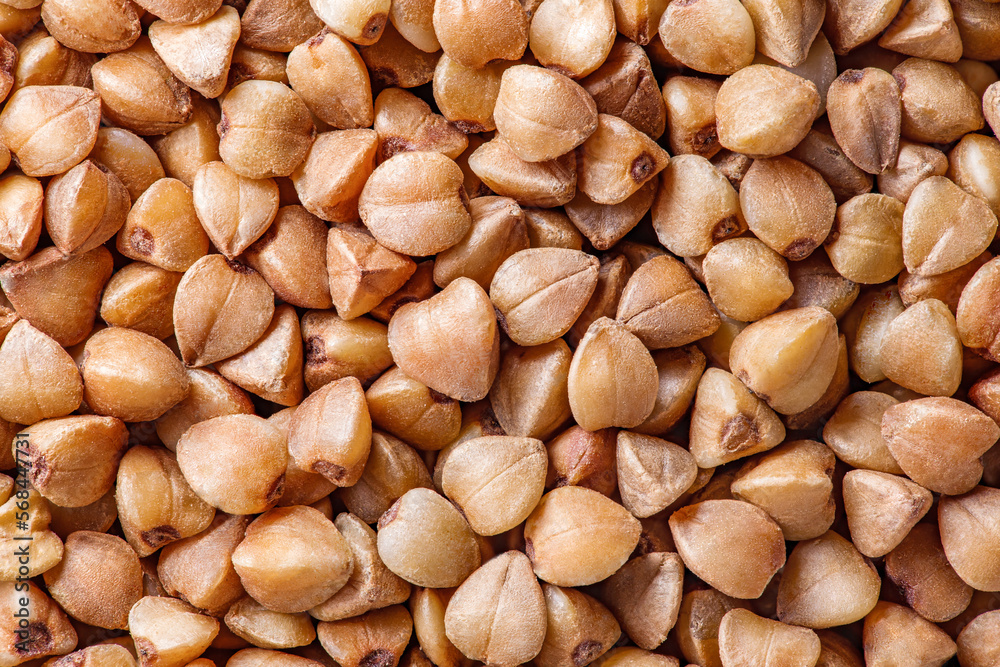 Buckwheat groats raw, small grains in bulk close-up, background wallpaper, uniform texture pattern