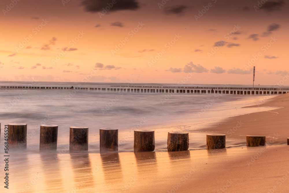 Landscape with waterbreak in the sea under the sky at sunset