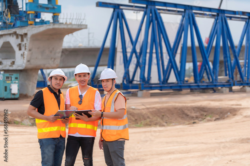 Group of asian engineers discuss about work at site of building under construction,The contractor team discusses the design of the structure,Three workers are working outside.