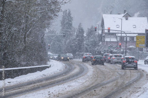 Schneebedeckte Strasse mit Fahrspuren, Fahrzeugen,Ampelanlage und Schneegestöber © lebaer