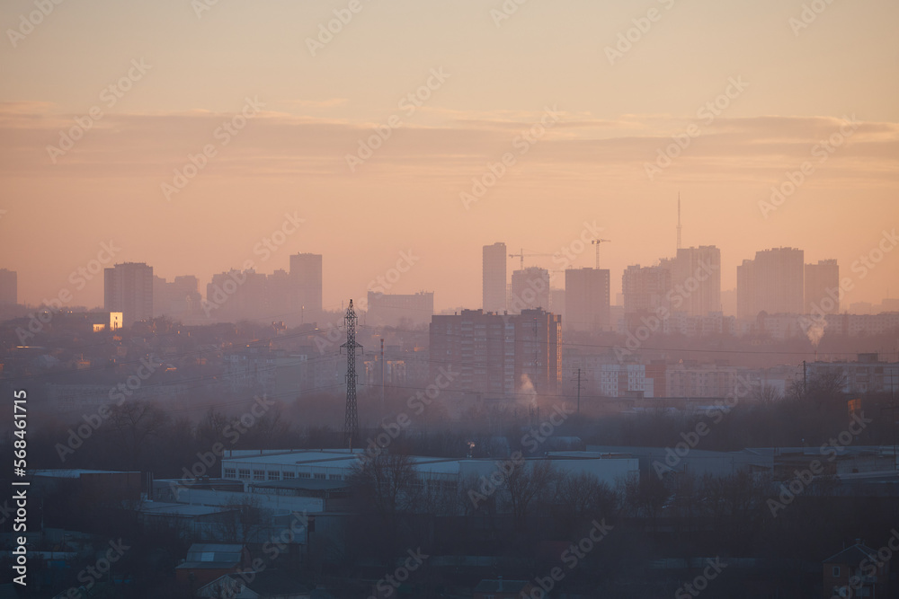 city at sunset, panorama of city, outlines of buildings, smog over industrial zone