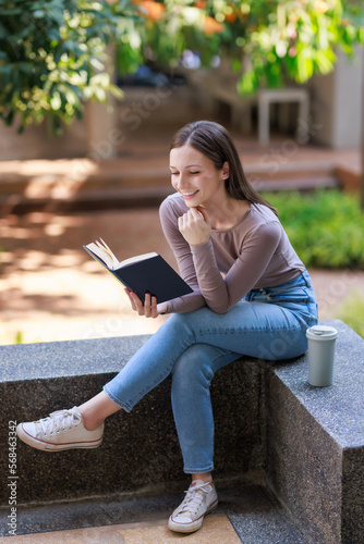 Beautiful young lady sitting on bench and exciting story book in park, enjoying lazy morning, having relaxing weekend