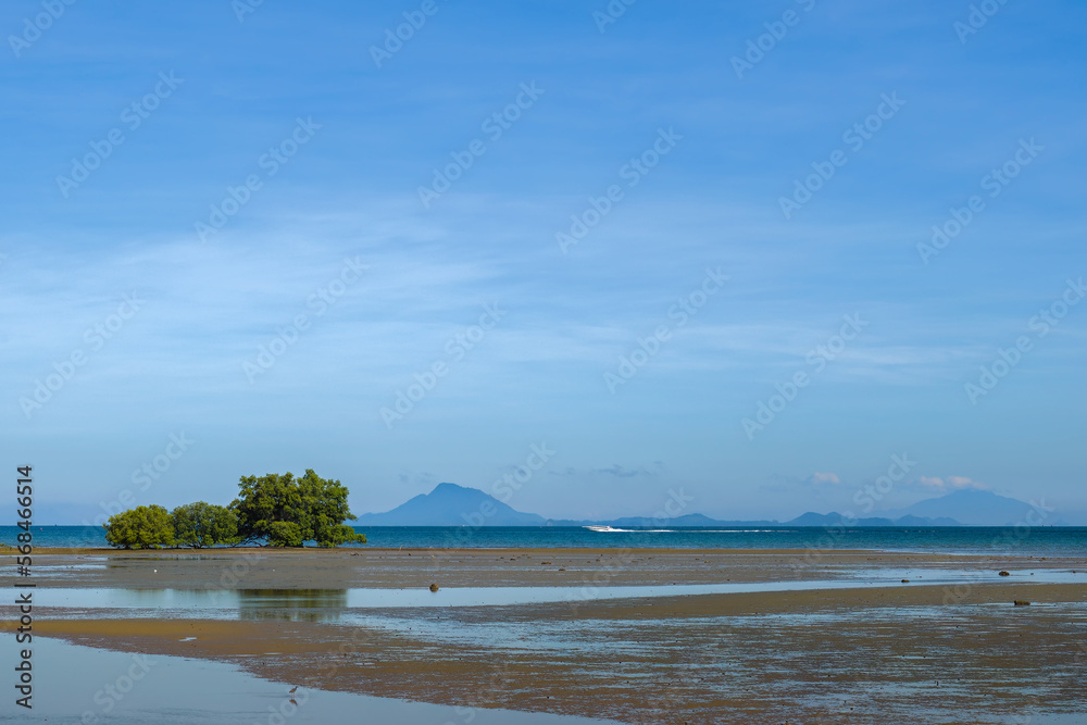 Tropical beach at low tide in Ko Lanta Island, Thailand with speedboat in the background