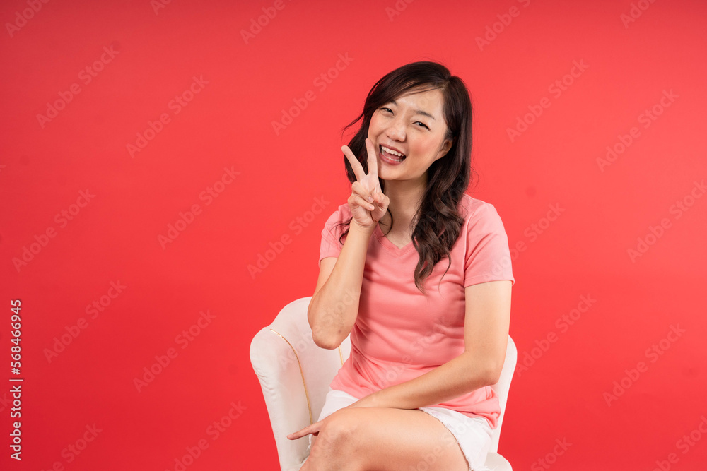 Happy beautiful Asian woman smile and make character V  on red background. New Year, Christmas and Valentines Day concept