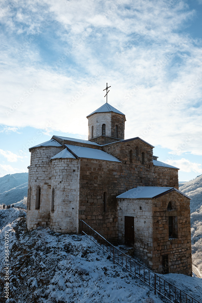 Fototapeta premium church on rock in snow, monastery on mountain, chapel, pagoda, winter landscape, snow on roof and slopes of mountains, church on rock