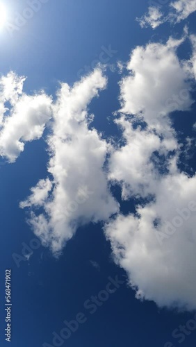 Vertical video of the blue sky with clouds and lens flare effect. 4K, real time. Sunny day.