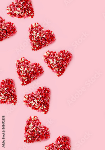 A lot of heaps sweets candies shape of heart on pink background