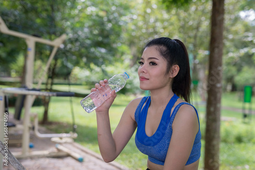 beautifull sport girl drinking water at the public park court and wearing blue sport bra