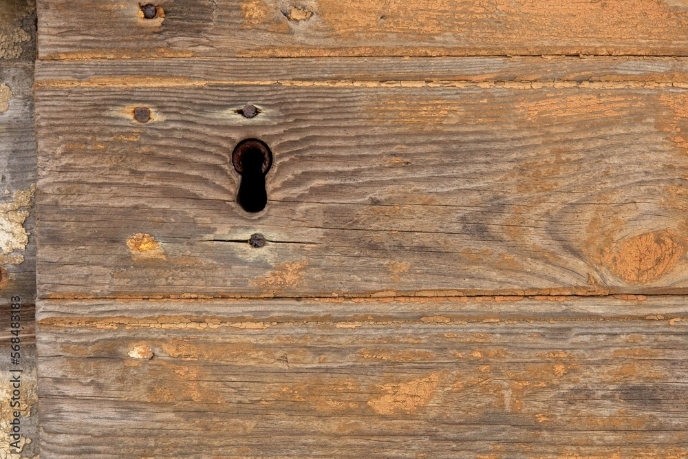 Obraz premium Keyhole on a old weathered wooden door with paint peeling off.