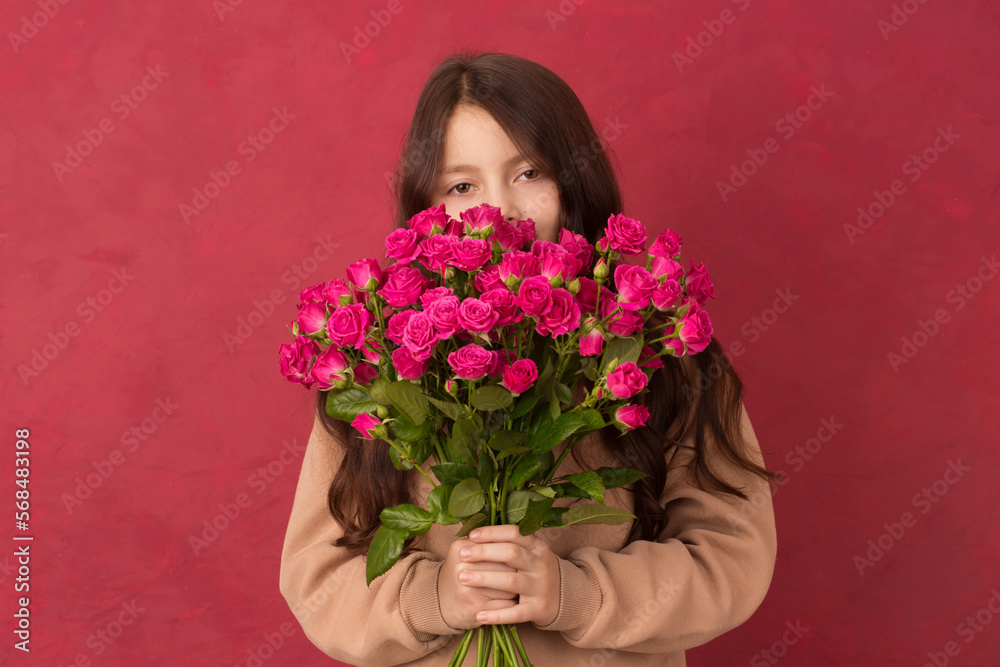 A teenage girl with a bouquet of beautiful pink roses of pink roses on a Viva Magenta color background A teenage girl with a bouquet of beautiful pink roses of pink roses on a Viva Magenta color background