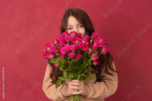 A teenage girl with a bouquet of beautiful pink roses of pink roses on a Viva Magenta color background