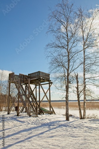 Wooden bird observation tower in winter in sunny weather at lake Ridasjärvi, Finland.