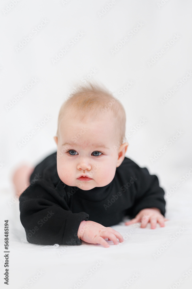 Portrait of a charming Caucasian baby in a stylish black bodysuit on a white background