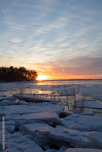 Sunset in winter on seashore with ice floe in sea and clouds in the sky, Mussalo, Kotka, Finland. photo