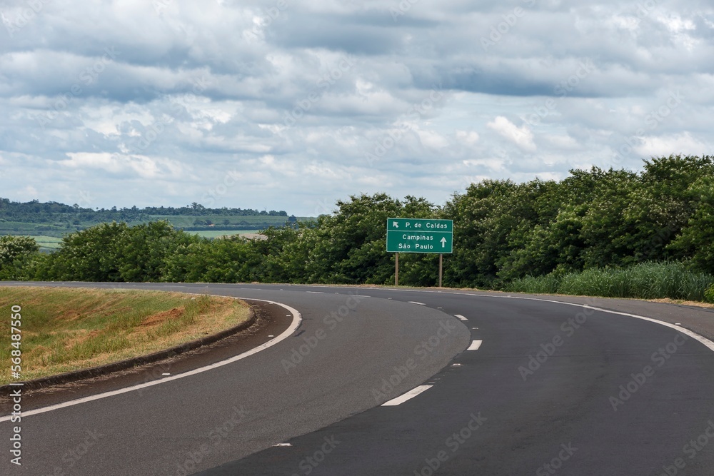 Curve in rural highway. Sign indicating access to the city of Poços de Caldas, Campinas and São Paulo.