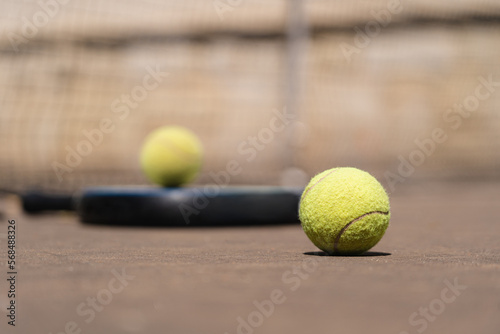 From above closeup of yellow padel balls placed on court near racket on sunny day © diignat