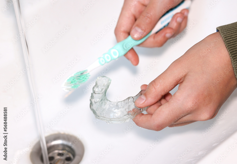Hand cleaning transparent  retainer with toothbrush and toothpaste over sink.  - obrazy, fototapety, plakaty 