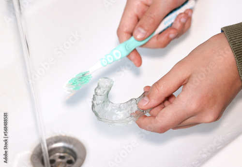 Hand cleaning transparent  retainer with toothbrush and toothpaste over sink. 