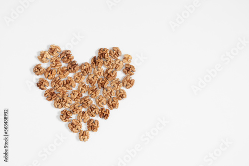 Walnuts are laid out in shape of heart on white background. Flat lay, top view, copy space 