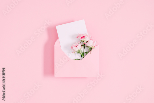 Top view on open pink envelope with paper card, bouquet of pink flowers rose on pastel pink table background. Birthday, Wedding, Mother's Day, Valentine's day, Women's Day. Flat lay, copy space © prime1001
