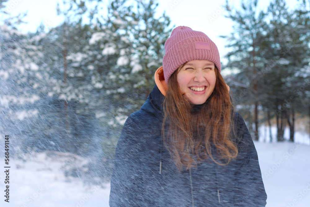 portrait of a beautiful cute girl in the park or forest, outdoors, woman having fun, laughing smiling at the nature. teenager in warm cloth. Blizzard and snow, snowflakes falling down portrait of a beautiful cute girl in the park or forest, outdoors, woman having fun, laughing smiling at the nature. teenager in warm cloth. Blizzard and snow, snowflakes falling down