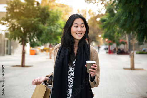 Young beautiful woman with a cup of coffee and shopping bag in the city - fasion concept