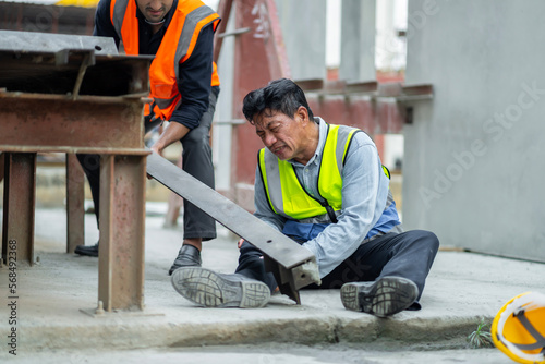 An engineer has an accident where steel falls on his leg at work, causing serious leg injuries. and get help from colleagues in the area under construction industrial factory, concept, safe work