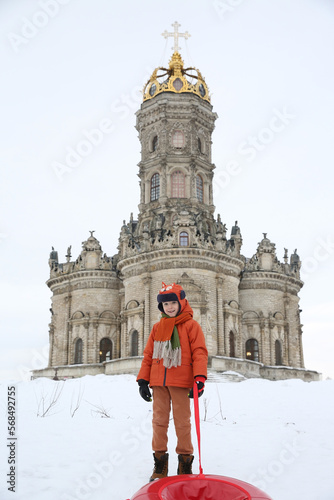 Сhild, fun kid, cute boy rides in the snow. Winter entertainment. Child rides the tube, tubing. Winter active game, outdoor rest, recreation. Сhild, kid plays with snow. Winter fashion, look, clothes photo