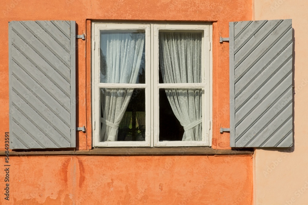 White wood framed window on a old building with grey painted exterior wood shutters. White wood framed window on a old building with grey painted exterior wood shutters.