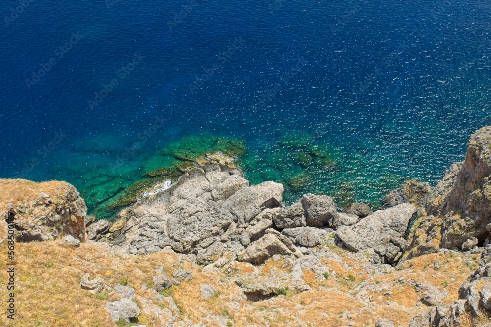 Downwards view of rocky seashore with clear water in spring, Lindos, Rhodes, Greece.
