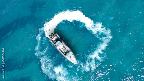 Aerial drone photo of inflatable rib boat cruising in low speed near tropical exotic island shore with crystal clear turquoise sea