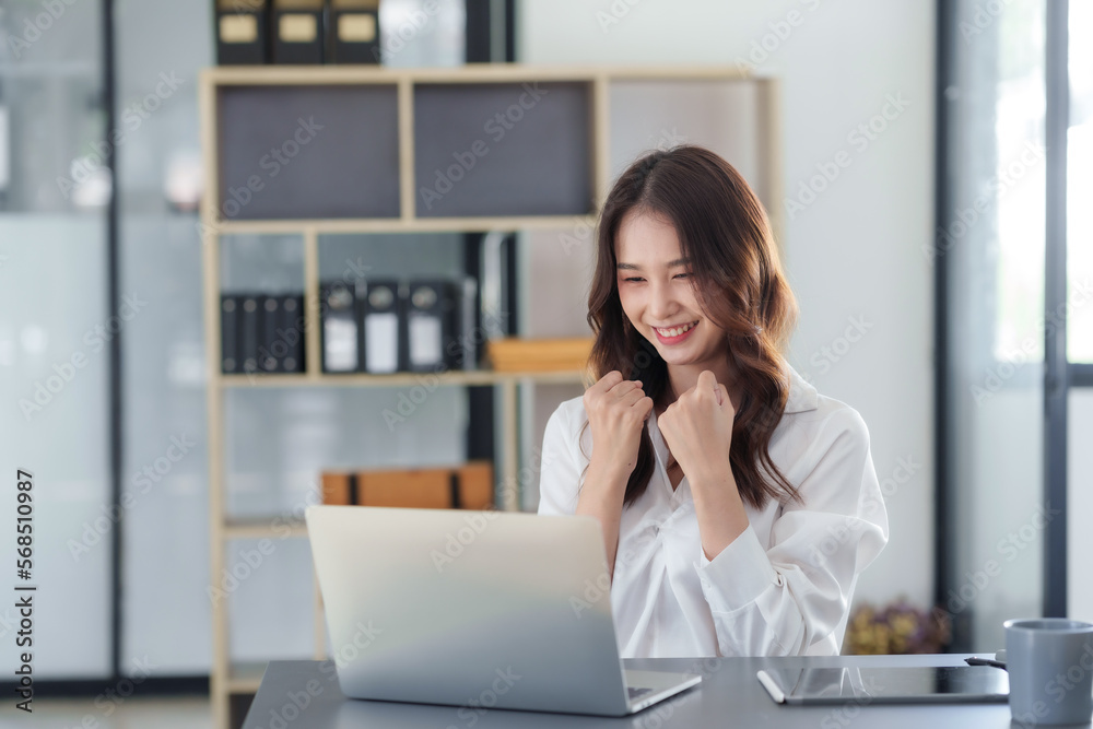 Attractive Asian businesswoman raising hands happily with successful plan with happy smile with laptop computer. Attractive Asian businesswoman raising hands happily with successful plan with happy smile with laptop computer.