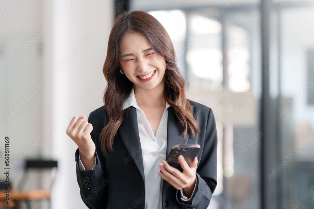 Happy young Asian business woman successful excited raised hands rejoicing with smartphone. Happy young Asian business woman successful excited raised hands rejoicing with smartphone.