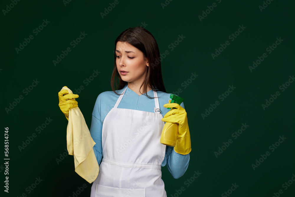 frowning woman cleaner apron with cleaning rag and detergent sprayer frowning woman cleaner apron with cleaning rag and detergent sprayer