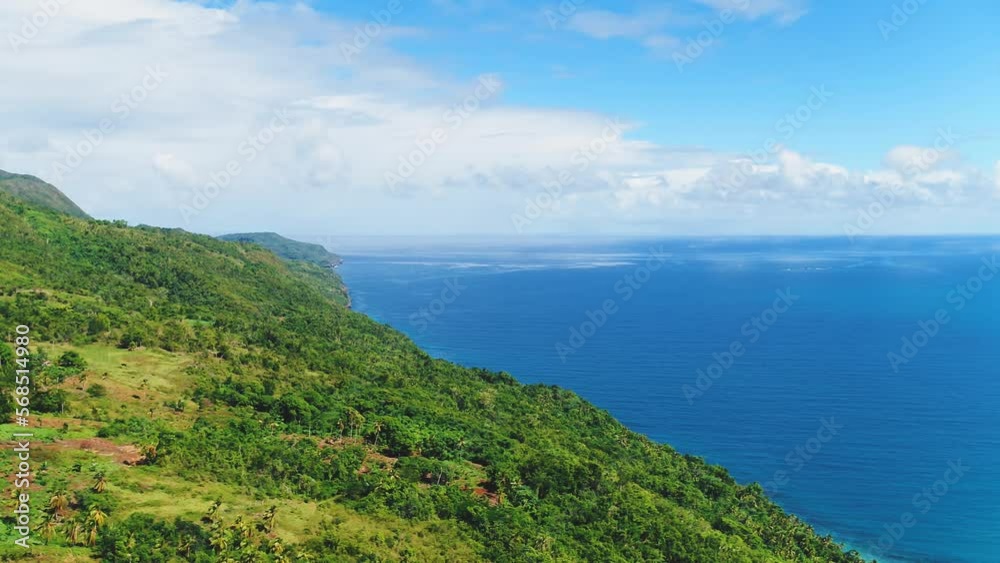 Beautiful sunny day in a mountain landscape on the Caribbean coast, aerial view. Green palm jungle against the blue ocean. Summer on a tropical hilly peninsula. Beautiful sunny day in a mountain landscape on the Caribbean coast, aerial view. Green palm jungle against the blue ocean. Summer on a tropical hilly peninsula.