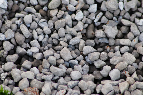 Gray raw rocks and rough stones as natural stones background with crushed and rough material as building material or rocky base for concrete mixture in gray colors as natural stones background