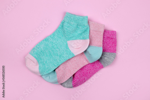 Stack of baby socks on pink background