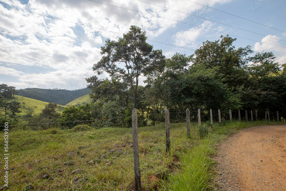dirt road with wooden fence and barbed wire in countryside of Sao Paulo state, Brazil