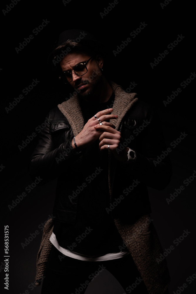Fototapeta premium mysterious bearded man with hat and glasses adjusting rings on fingers