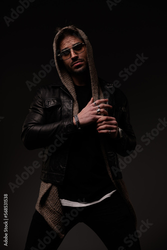 confident cool man with hoodie wearing leather jacket and wool cardigan