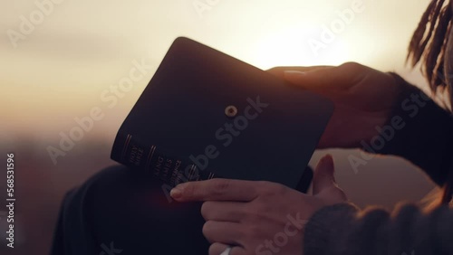 Close-up. A woman opens a Bible, flips through the pages. A girl reads the Bible in the open air, studies the word of God at sunset on top of a mountain. Finding Truth in the Scriptures. High quality 