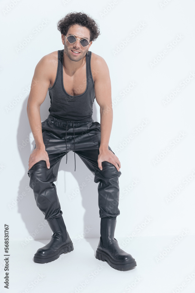 sexy man with curly hair in undershirt smiling and laying on a wall sexy man with curly hair in undershirt smiling and laying on a wall