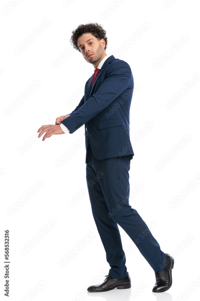 side view of sexy turkish guy in suit arranging sleeves and walking side view of sexy turkish guy in suit arranging sleeves and walking