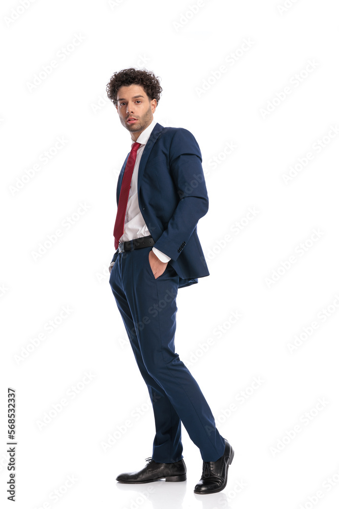 side view of elegant businessman with curly hair posing with hands in pockets side view of elegant businessman with curly hair posing with hands in pockets