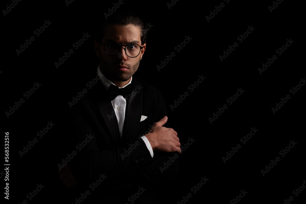 mysterious elegant man in black tuxedo folding arms