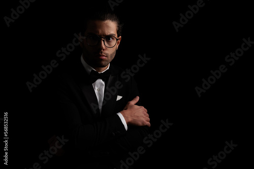 mysterious elegant man in black tuxedo folding arms