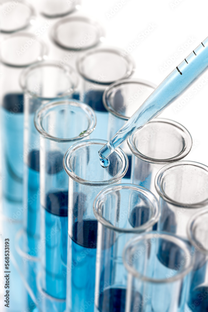 Laboratory glassware with a dropper dripping liquid into a test tube. scientific laboratory test tubes,